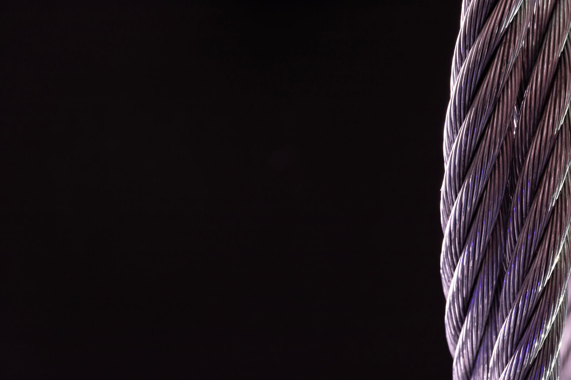 Detailed close-up of a silver twisted cable against a black background, perfect for industrial themes.
