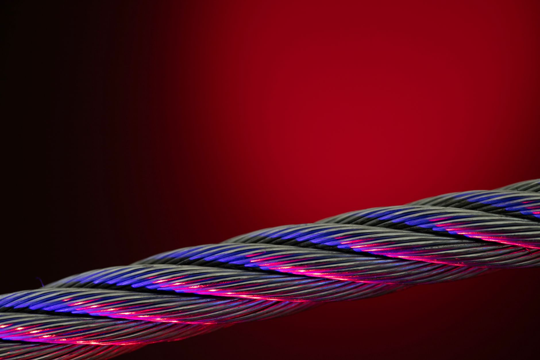 Close-up of a colorful twisted wire against a vivid red background.