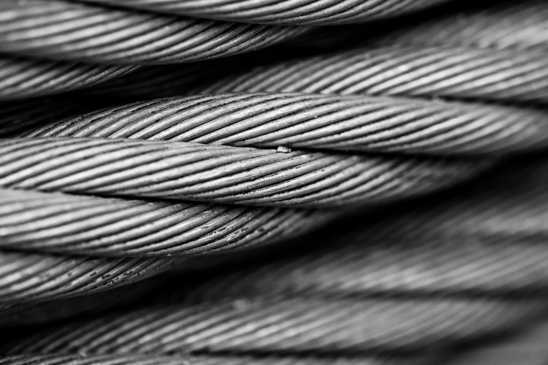 Detailed black and white macro photo of twisted steel cables. A study in texture and pattern.