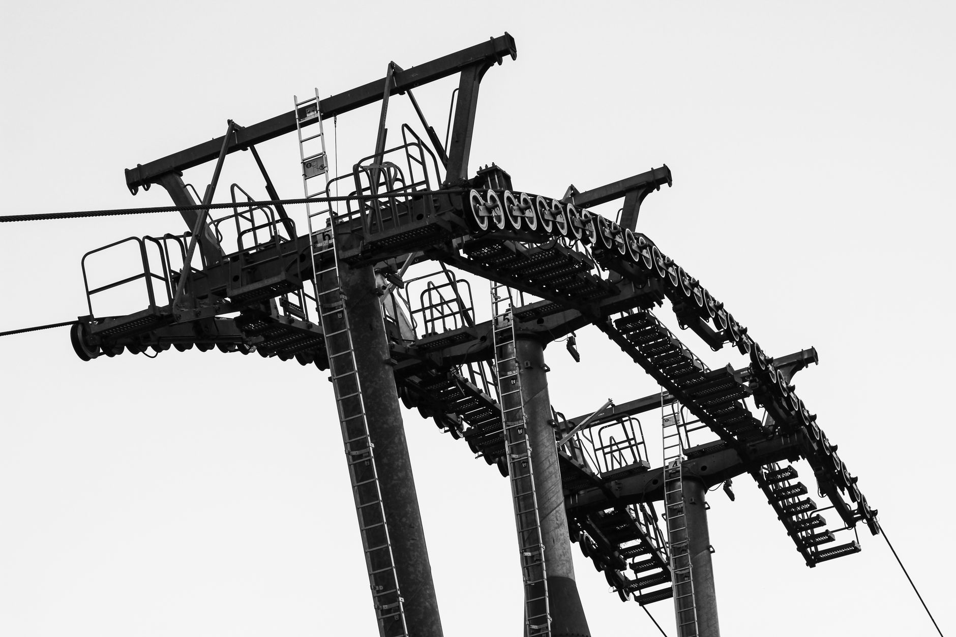 Black and white photograph of a tall industrial cable tower with ladders and machinery.